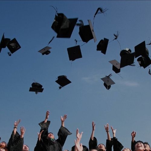 Estudiantes universitarios graduados tirando su birrete al cielo